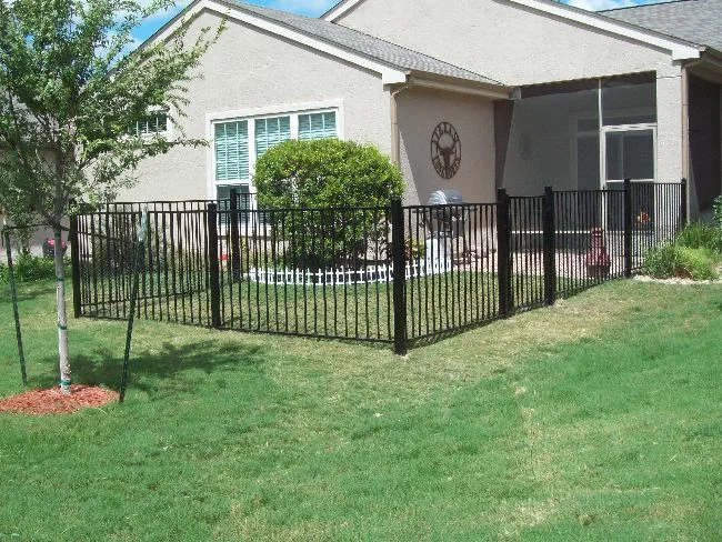 Black ornamental iron fence enclosing the front yard of an Austin home